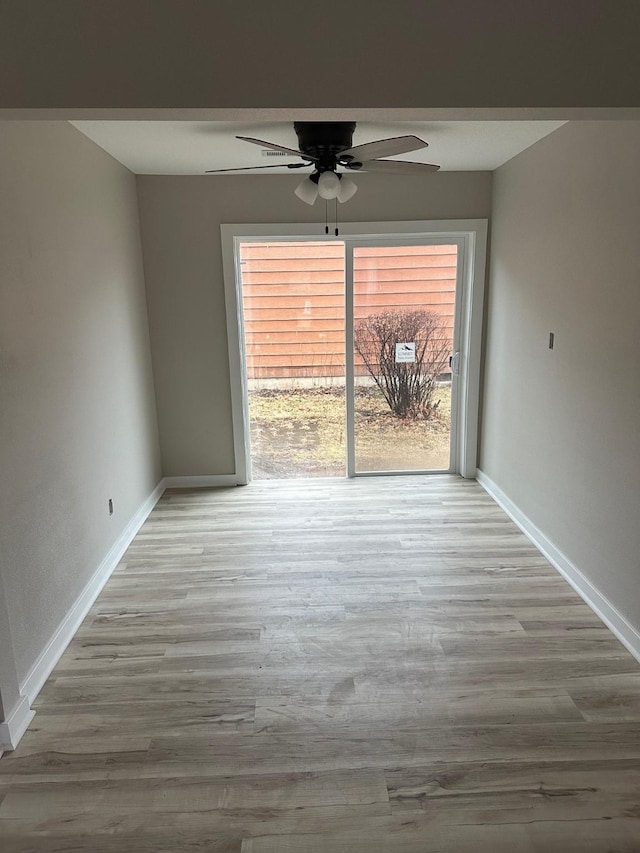 interior space featuring a ceiling fan, baseboards, and wood finished floors