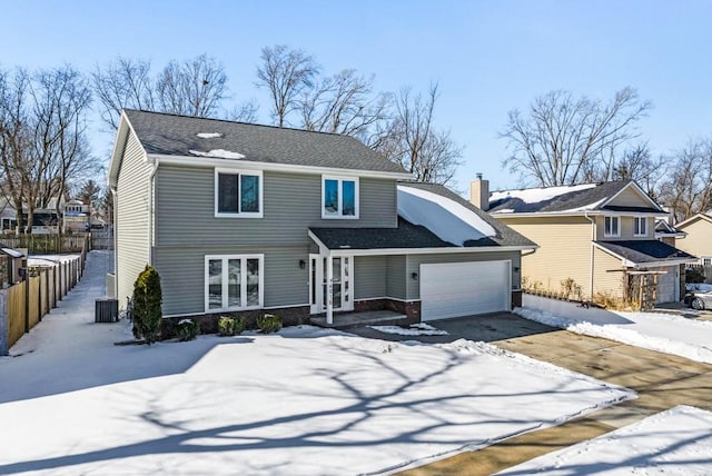 traditional home with a shingled roof, fence, a garage, cooling unit, and driveway