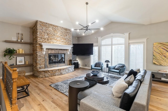 living area with lofted ceiling, a fireplace, wood finished floors, and a notable chandelier