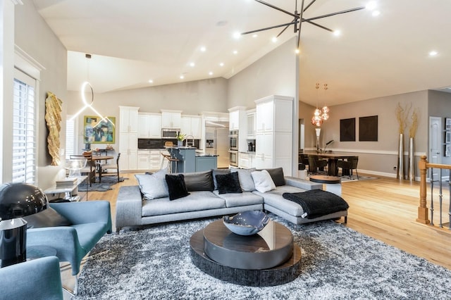 living room with a chandelier, light wood-type flooring, high vaulted ceiling, and recessed lighting