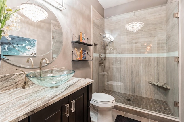 bathroom with a notable chandelier, a shower stall, and toilet