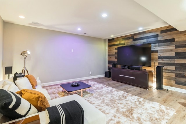 living room with wood walls, an accent wall, wood finished floors, and recessed lighting