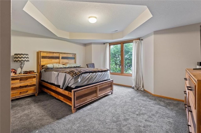 carpeted bedroom with a raised ceiling, a textured ceiling, and baseboards