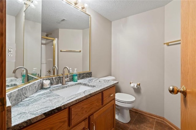 full bath with a textured ceiling, tile patterned flooring, toilet, vanity, and a shower with door