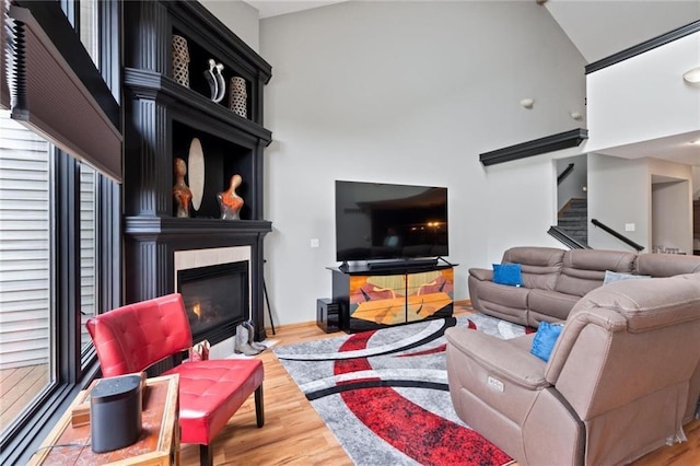 living area with stairway, a fireplace, wood finished floors, and baseboards