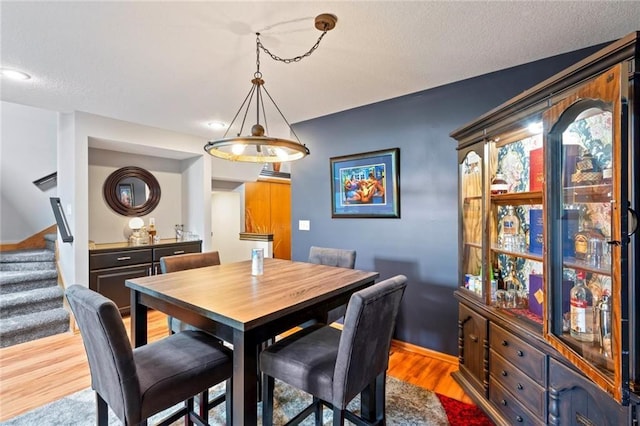 dining room featuring baseboards, a textured ceiling, stairway, and wood finished floors