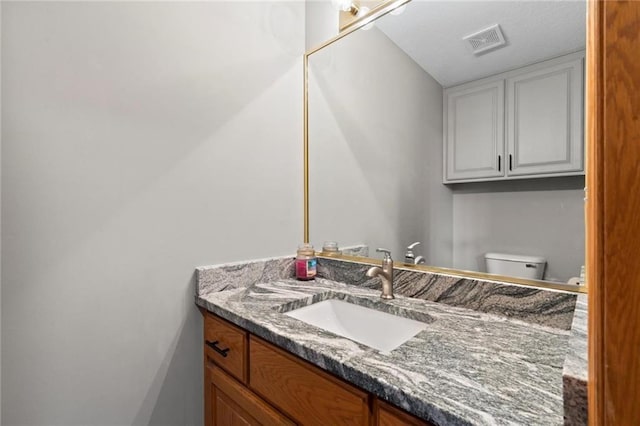 half bath featuring toilet, vanity, and visible vents