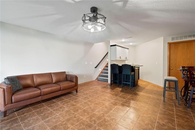 tiled living room featuring stairs, a dry bar, a textured ceiling, and visible vents