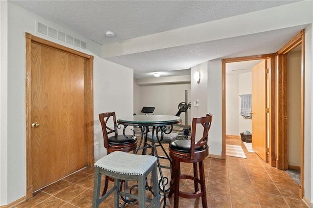 tiled dining space with baseboards, visible vents, and a textured ceiling