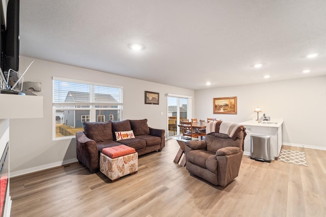 living area featuring baseboards, recessed lighting, and light wood-style floors