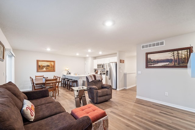 living area featuring recessed lighting, visible vents, light wood-style flooring, and baseboards