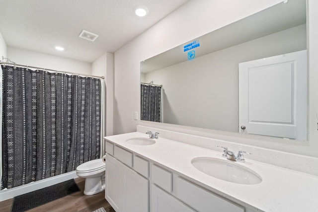 full bath with toilet, visible vents, a sink, and wood finished floors