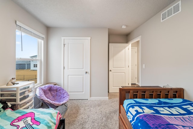 bedroom featuring baseboards, carpet, visible vents, and a textured ceiling