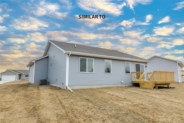 rear view of house featuring a shingled roof, cooling unit, a lawn, and a deck