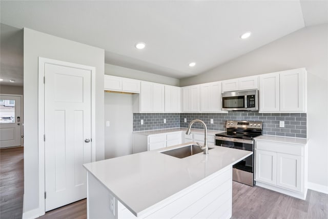 25091 Bluebird Cir, Adel, IA 50003 - kitchen with appliances with stainless steel finishes, light wood-type flooring, lofted ceiling, white cabinets, and backsplash