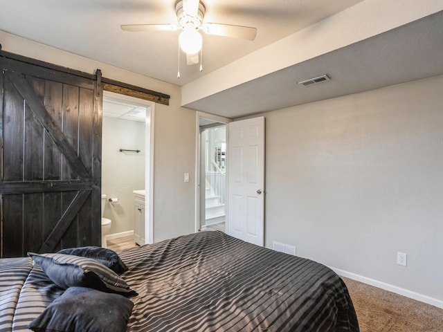 bedroom featuring carpet floors, a barn door, visible vents, and baseboards