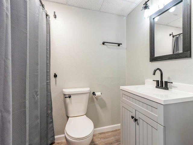 full bath with a paneled ceiling, baseboards, toilet, and vanity