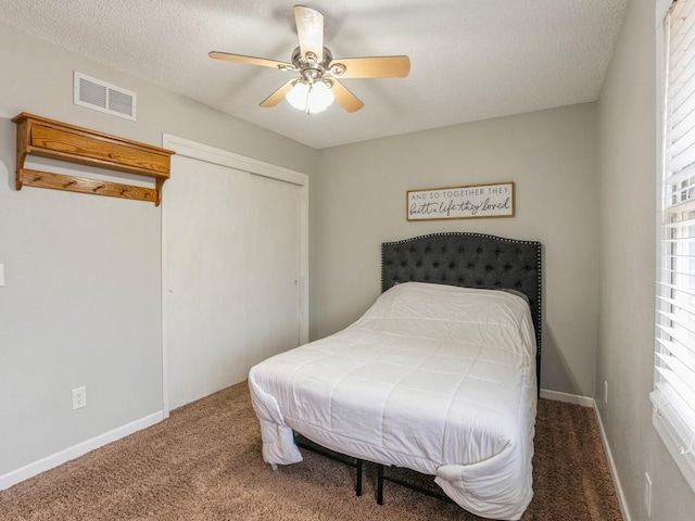 carpeted bedroom with a textured ceiling, a closet, visible vents, and baseboards