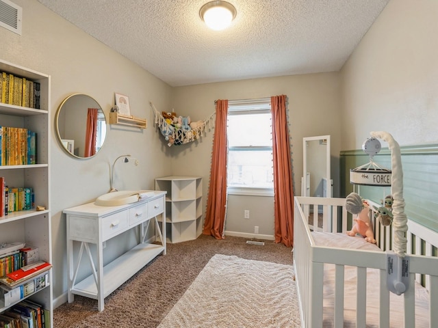 bedroom featuring baseboards, a textured ceiling, visible vents, and carpet flooring