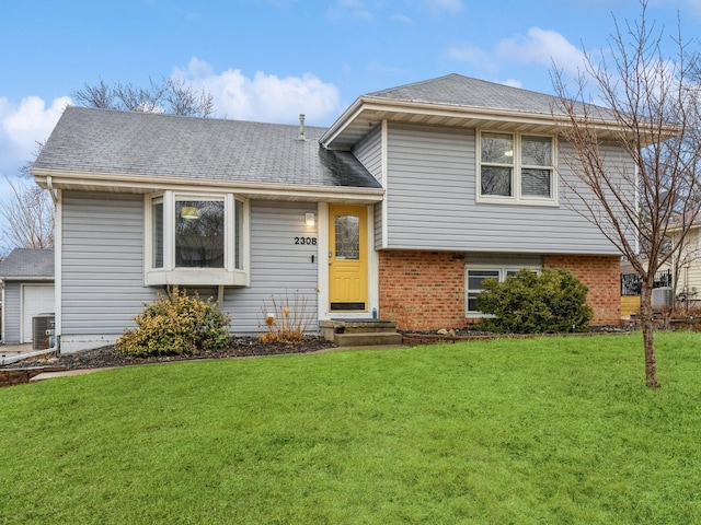 tri-level home featuring brick siding, roof with shingles, a front lawn, and central air condition unit