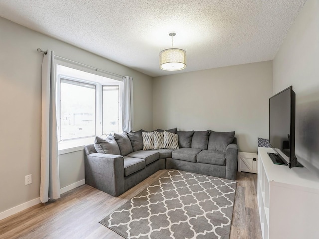 living room with light wood-style flooring, baseboards, and a textured ceiling