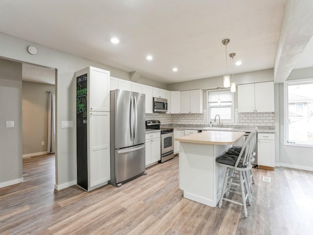 kitchen featuring appliances with stainless steel finishes, backsplash, a sink, and light wood-style floors