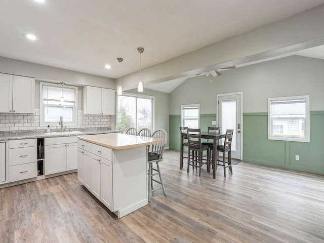 kitchen with lofted ceiling, light countertops, a sink, and a kitchen breakfast bar