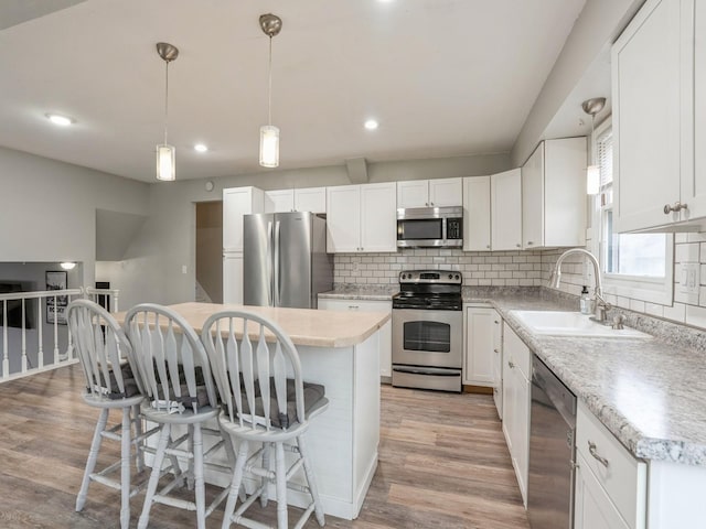 kitchen featuring light wood-style floors, stainless steel appliances, a sink, and a kitchen breakfast bar