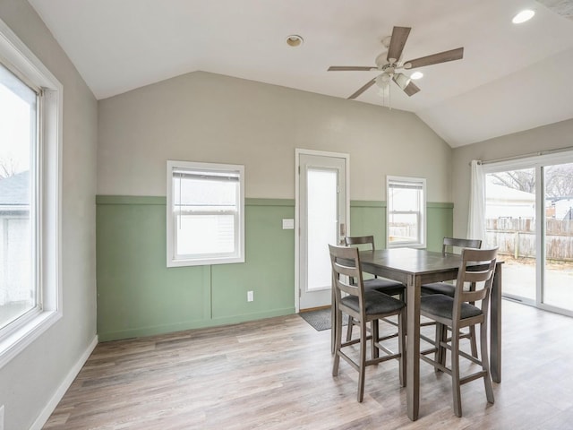 dining room featuring a ceiling fan, vaulted ceiling, light wood-style flooring, and baseboards