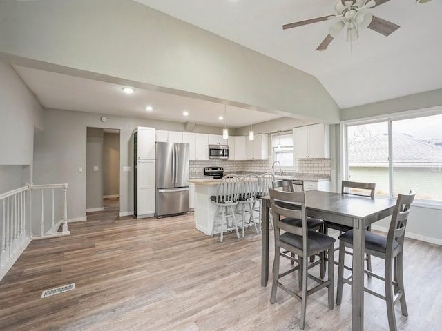 dining area featuring lofted ceiling, light wood-type flooring, visible vents, and baseboards