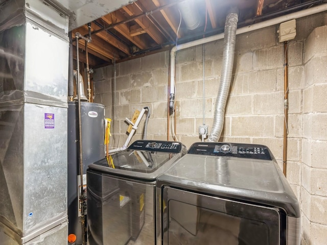 washroom with heating unit, laundry area, water heater, and washer and clothes dryer