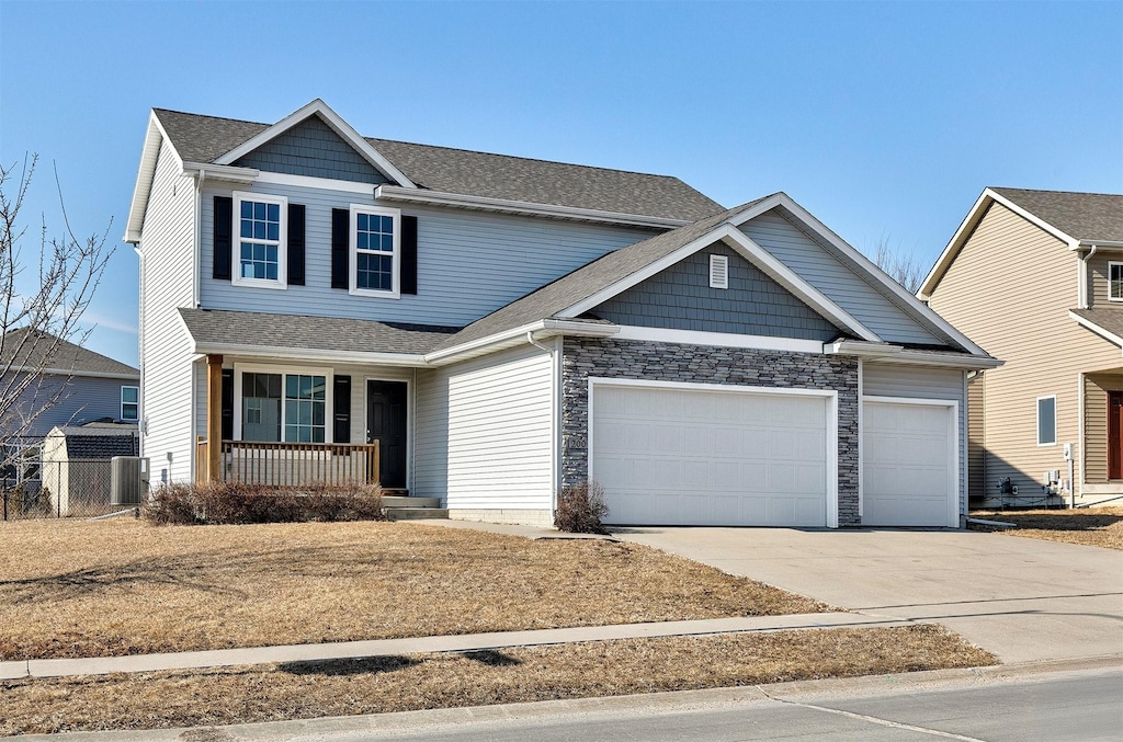 view of front facade featuring driveway, a garage, stone siding, a porch, and central AC