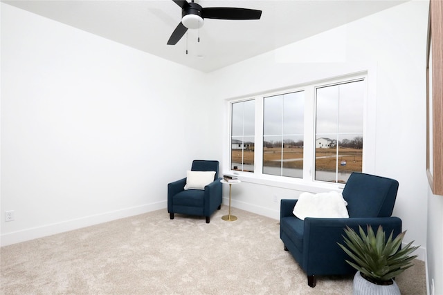 living area featuring carpet, baseboards, and ceiling fan