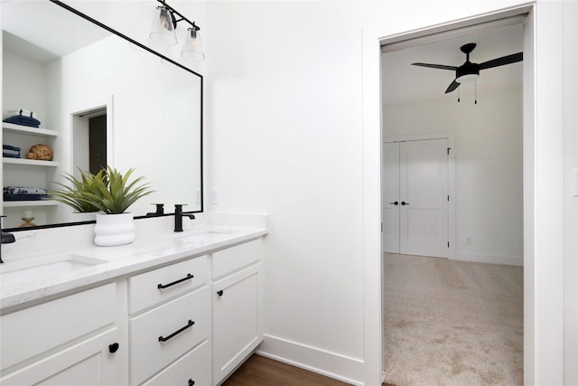 full bath with double vanity, baseboards, a ceiling fan, and a sink