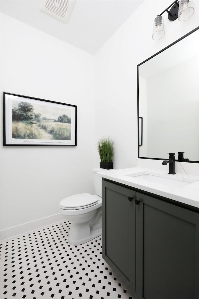 half bath with baseboards, visible vents, vanity, and toilet