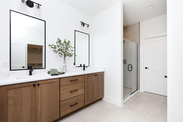 full bath with double vanity, a shower stall, baseboards, and a sink