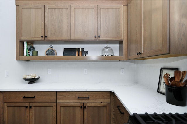 kitchen featuring light stone counters, backsplash, and open shelves