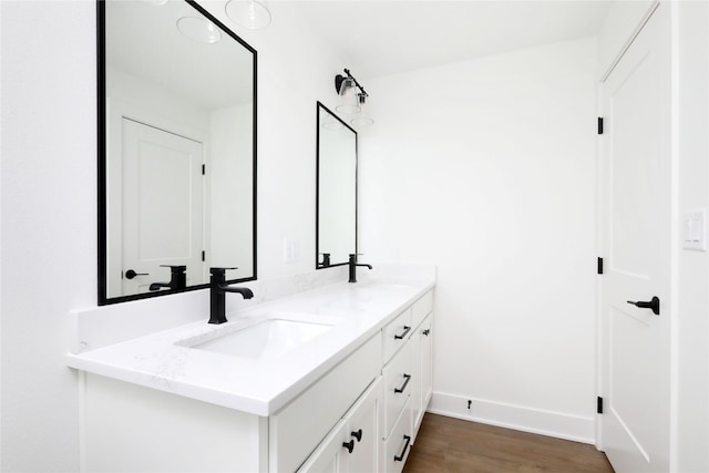 bathroom featuring double vanity, baseboards, a sink, and wood finished floors