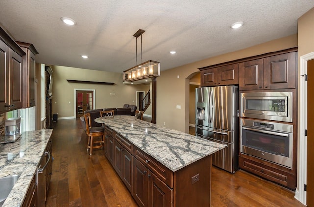 1306 NE 45th St, Ankeny, IA 50021 - kitchen with appliances with stainless steel finishes, arched walkways, dark wood finished floors, a center island, and recessed lighting