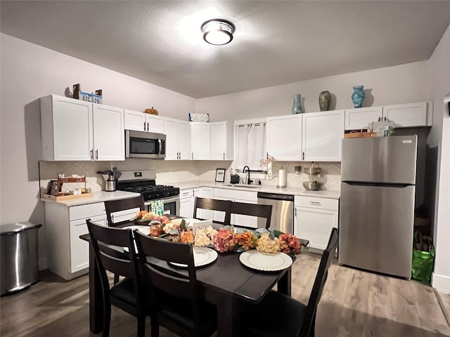 kitchen with appliances with stainless steel finishes, light countertops, a sink, and white cabinetry