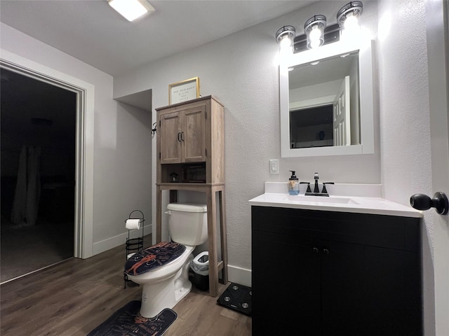 bathroom with baseboards, vanity, toilet, and wood finished floors