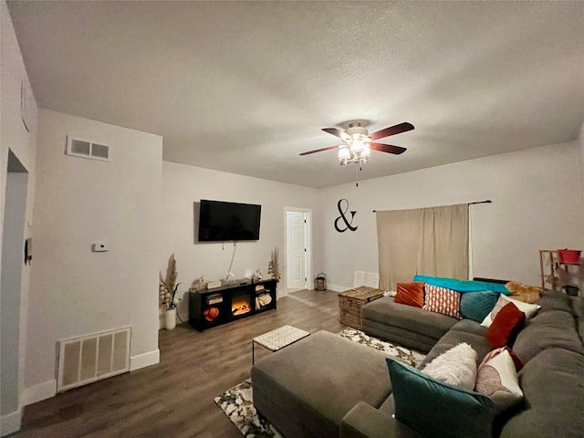 living room featuring baseboards, ceiling fan, visible vents, and wood finished floors