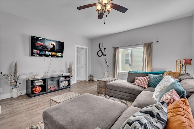 living area featuring a ceiling fan, baseboards, and wood finished floors