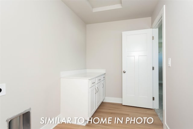 clothes washing area featuring light wood-style flooring and baseboards