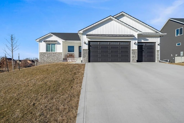 view of front of property with an attached garage, driveway, stone siding, board and batten siding, and a standing seam roof