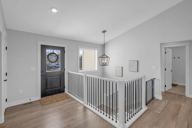 entryway featuring lofted ceiling, light wood-style floors, baseboards, and visible vents