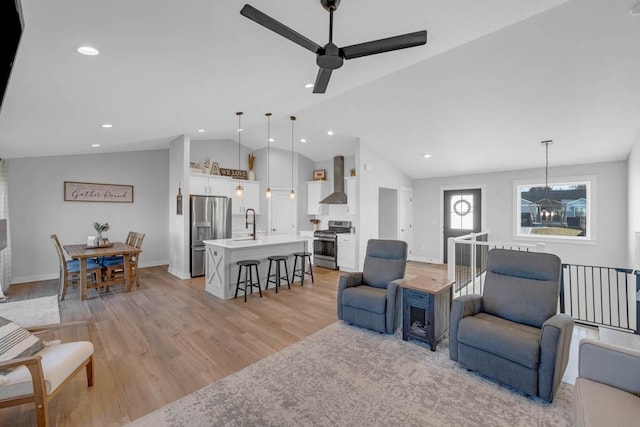 living room featuring light wood-type flooring, lofted ceiling, recessed lighting, and ceiling fan with notable chandelier