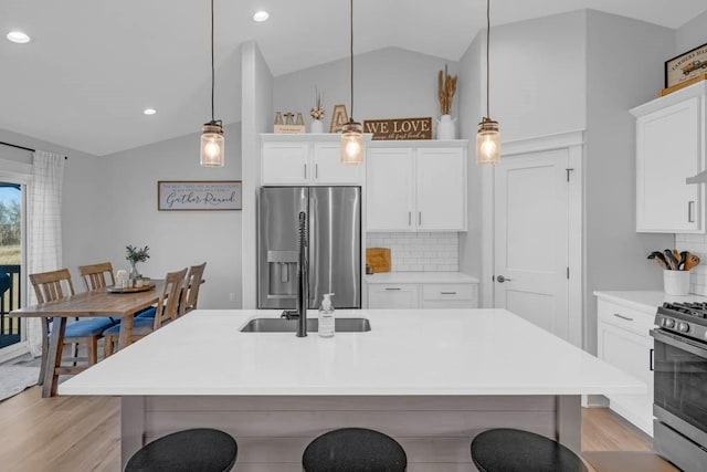 kitchen with decorative backsplash, lofted ceiling, a breakfast bar area, stainless steel appliances, and light countertops