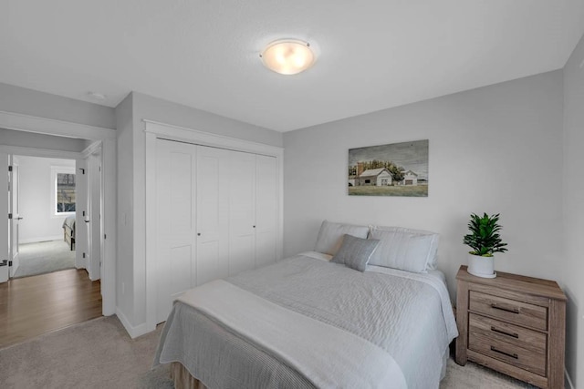 bedroom featuring a closet, light carpet, and baseboards