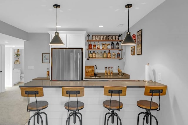 bar featuring light carpet, a sink, hanging light fixtures, freestanding refrigerator, and indoor wet bar